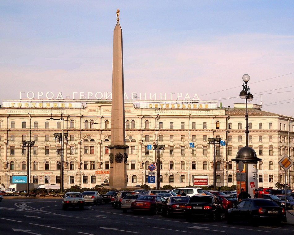 Eine der Heldenstadt gewidmete Leuchtreklame ist am Platz des Aufstands in Sankt Petersburg hinter dem Goldenen Stern der Helden der Sowjetunion installiert / Foto © Fjodor Gusljarow/Wikipedia unter CC BY-SA 3.0