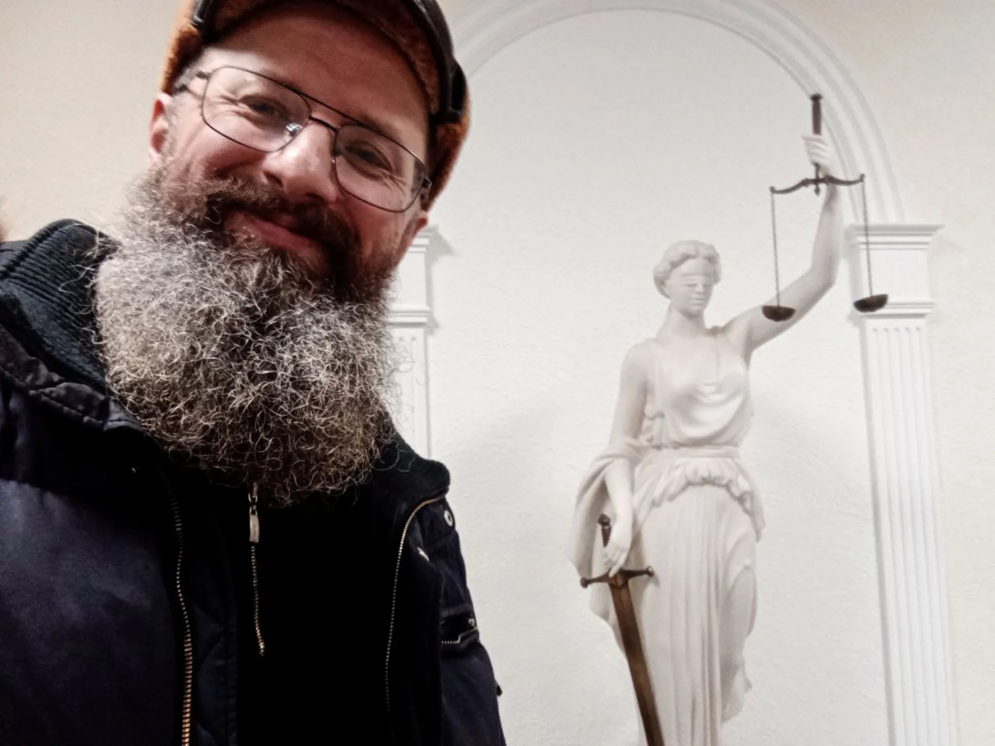 Dmitri Skurichin posiert vor einer Statue der Justitia. Er war seit vielen Jahren politisch aktiv, auch als Abgeordneter. Für seinen Protest gegen den Krieg schickte ihn ein Gericht für anderthalb Jahre in ein Straflager / Foto © privat