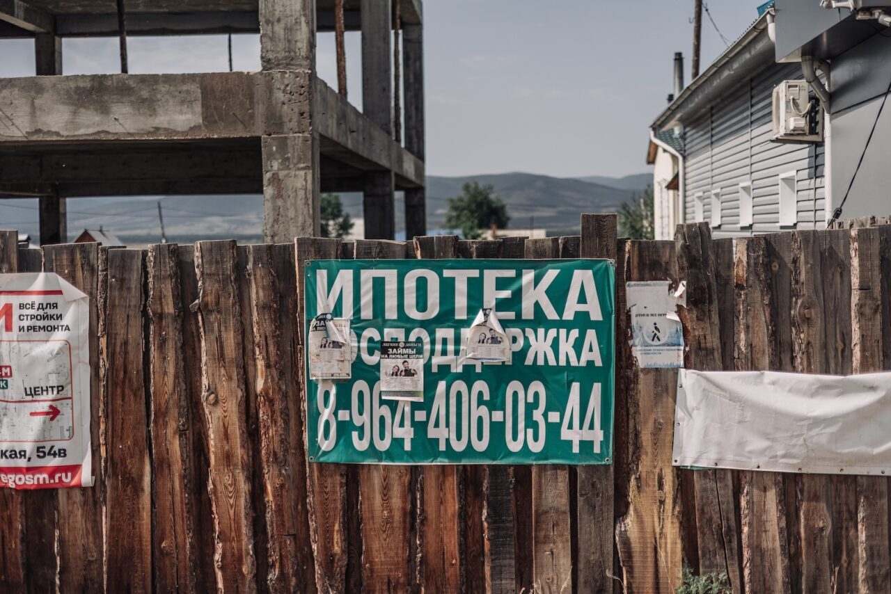 Werbung für Hypotheken vor Bauruine und Hausneubau im Kreis Iwolginsk, Burjatien / Foto © Ljudi Baikala